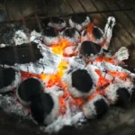 Briket arang menyala di atas panggangan, siap digunakan untuk keperluan memasak atau shisha